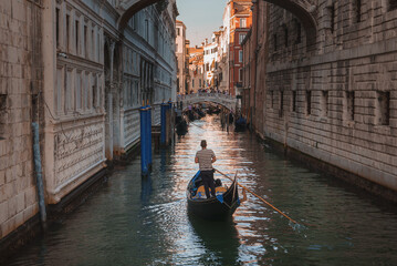Fototapeta na wymiar A serene gondola glides peacefully down a canal in Venice, capturing the timeless and romantic allure of the iconic city on a clear summer day.