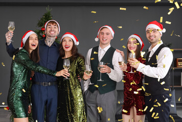 Young coworkers with champagne and confetti celebrating New Year at corporate party in office