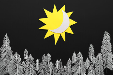 Paper sun with crescent and drawn fir trees on dark background. Winter solstice concept