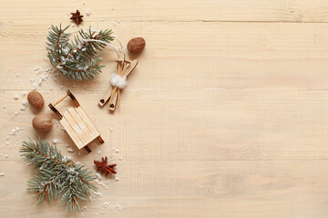 Wooden toys with snow, nuts and fir branches on light wooden background. Winter solstice concept
