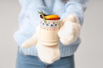 Young African-American woman with cup of hot mulled wine on grey background