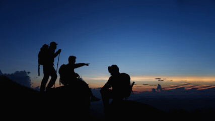 Silhouette of Asian teamwork standing raised hands with trekking poles and Backpack and other...