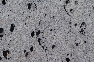 The surface of the grunge concrete wall is covered with cracks and holes.