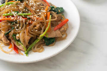 japchae or stir-fried Korean vermicelli noodles with vegetables and pork topped with white sesame