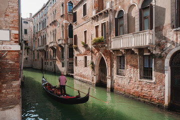 Fototapeta na wymiar A serene gondola glides along a picturesque canal in Venice, Italy. The timeless image captures the essence of the city's romantic waterways and historic charm.