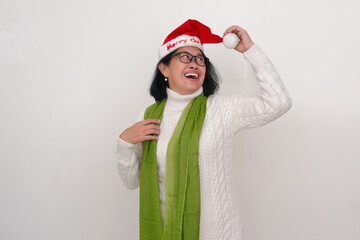 An Asian woman wearing a green shawl over a white sweater and a Santa Klaus's hat; smiling, happy...