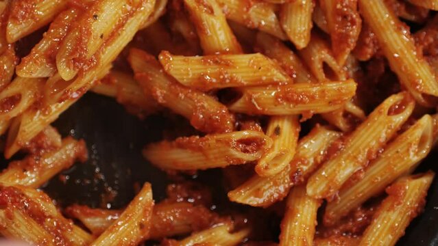 Cooking traditional arrabbiata pasta, penne with tomato sauce top view. Cook classic homemade Italian tomato sauce for pasta and pizza in the pan. Chef cooks traditional Italian food. 