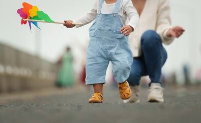 close up leg of infant baby walking on path with mother helping