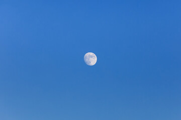 Full moon floating in the blue sky.