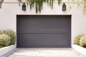 Secured garage door, black color, white concrete structure, long ivy type of plants