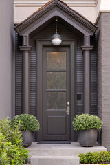 Front door with muted black color and frosted glass window.