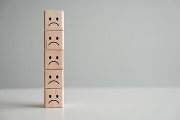 Sadness or unhappy face on stack of wooden block.no passion, feel sad, emotion, negative thinking, depressed, burnout syndromes, Low energy, world mental health day, mental health assessment concept.