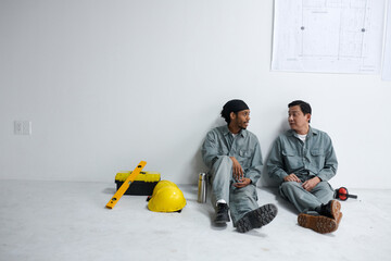 Construction workers chatting when resting on floor during short coffee break