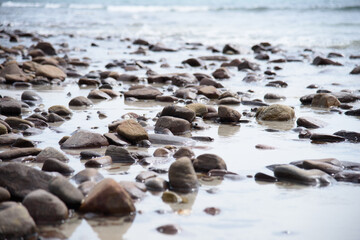Rocks/stones on the  beach during a daylight on the islands, Thailand.Background image of the beach with sea in the distance with pebble stones.
