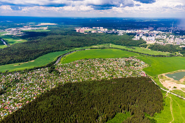 Panoramic view from a high altitude of dense dacha buildings outside the city among fields and...
