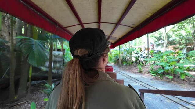 Women sightseeing riding on scenic train traveling through an enchanting lush tropical location.