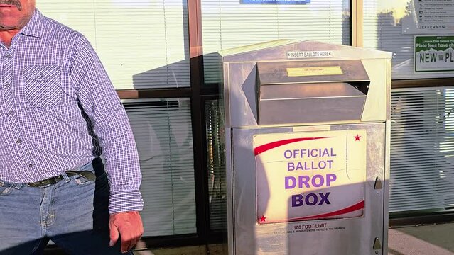 Latino Man Votes in Election by Dropping Mail-in Ballot Letter in Slot at Voting Booth with Offical Ballot Drop Box Sign for Democratic Government Campaign in Presidential Race