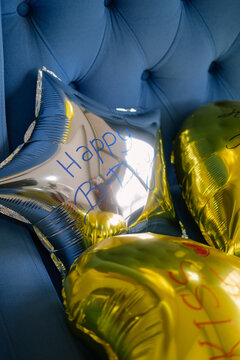 Birthday decorations - star and heart shaped balloons on a blue armchair background