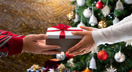 Man and woman exchanging a surprise gift – Closeup photo..Couple hands Christmas present.