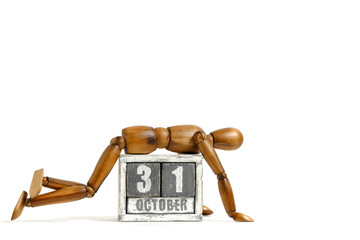 October 31, wooden calendar with mannequin lying on it on white background. Calendar date.