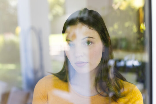 Portrait Of Thoughtful Caucasian Woman Looking Through Window At Home, Copy Space