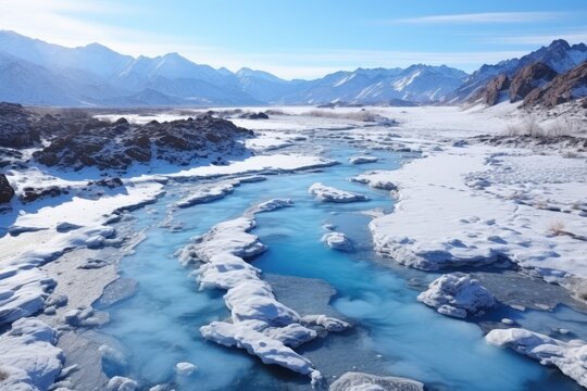 Arctic Flow: The Winter Sun Illuminates a Frozen River Winding Through a Snow-Kissed Mountain Landscape