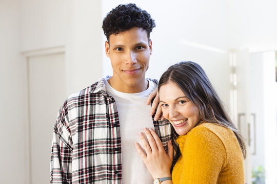 Portrait of happy diverse couple embracing at home, copy space