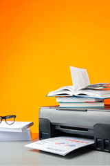 Laser printer on desk against yellow background.