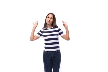 Fototapeta na wymiar smiling slender young brunette woman with straight hair dressed in a striped t-shirt indicates with her hands a gesture of ok