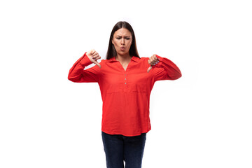 young sad brunette caucasian model woman dressed in trendy red blouse showing dislikes on white background