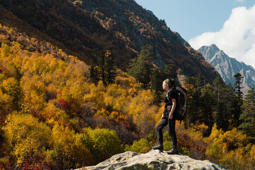 a girl with a backpack stands in the autumn mountains