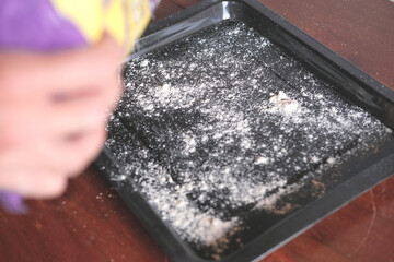 Hand with packet of flour and baking sheet with flour, top view