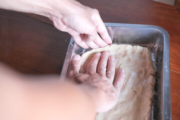 Hands kneading dough on backing sheet, close up
