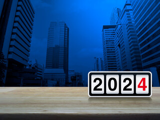 Retro flip clock with 2024 text on wooden table over modern city tower and skyscraper, Happy new year 2024 cover concept