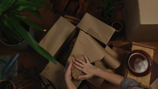 Household moving. Hands wrapping crockery and packing it in moving box.