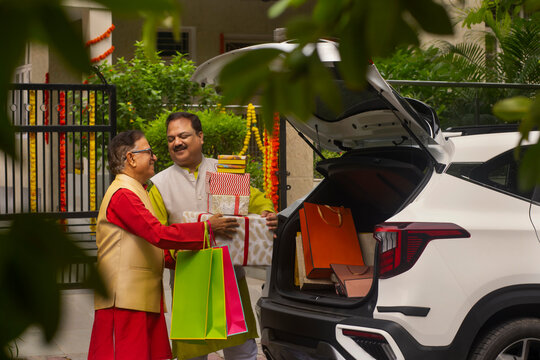 Father and son unloading Diwali gifts from car trunk after shopping