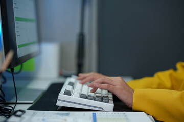 Successful Asian businesswoman sitting at desk typing numeric data on PC keyboard in modern office Business technology career concept.