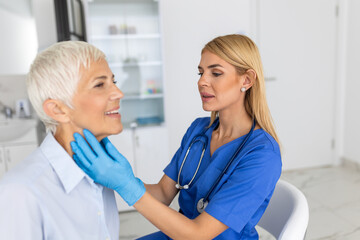 Friendly woman doctor wearing gloves checking sore throat or thyroid glands, touching neck of senior female patient visiting clinic office. Thyroid cancer prevention concept