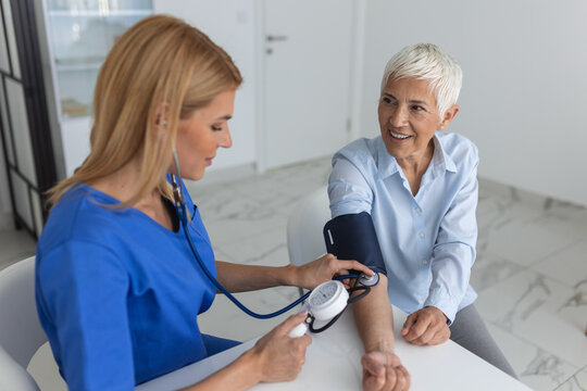 Doctor using sphygmomanometer with stethoscope checking blood pressure to a patient in the hospital.