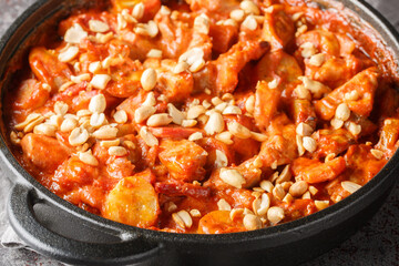 Classic Swedish Dish Flygande Jakob made of chicken, cream, chilli sauce, bananas, roasted peanuts and bacon closeup on the pan on the table. Horizontal