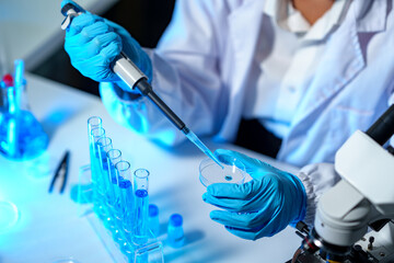 Fototapeta premium research laboratory. Female scientist uses micro pipette to release chemical liquid into test tube petri dish for test analysis for medicine. Concept of scientific research and development in biology