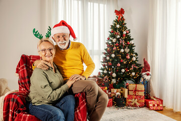 Obraz na płótnie Canvas Portrait of a festive happy senior couple spending christmas holidays at cozy home.
