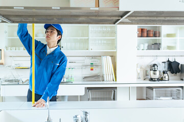 キッチンの棚を測量する男性作業員　内装業者