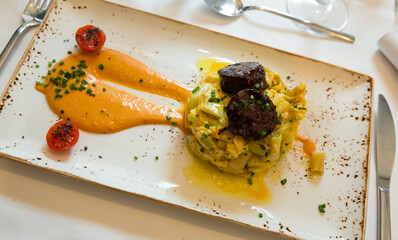 Tasty scrambled eggs with stewed green beans served with blood sausage and delicate romesco