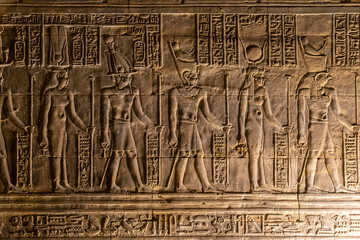 Ancient egyptian hieroglyphs carved on golden wall of Edfu Temple
