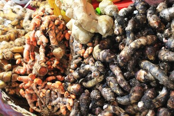 Closeup pile of ginger, turmeric and other tropical roots used for cooking ingredients for sale at an outdoor market in Southeast Asia