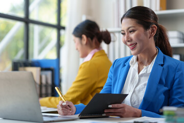 Obraz premium Creative team of business women sitting together at office Presentation of business performance and analysis Save financial, tax, income, and accounting charts and graphs on an office laptop.