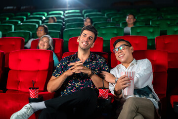 gay couple sweet and watching cinema together on red seat in theater,