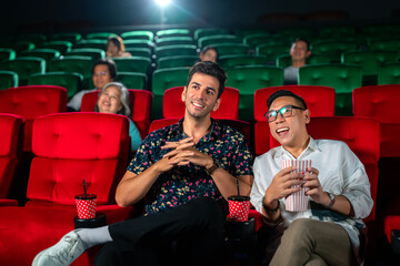 gay couple sweet and watching cinema together on red seat in theater,