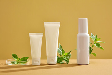Obraz na płótnie Canvas Front view of cosmetic bottles with different shape displayed on brown background with leaves of spearmint. Mockup scene for advertising. Space for design